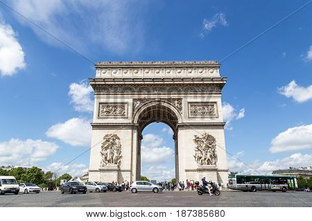 Paris, France - May 13, 2017: The Arc de Triomphe against a blue sky with traffic in front of it
