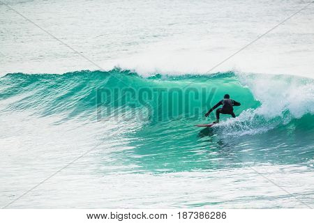 Surfing in turquoise barrel in ocean. Surfer on wave