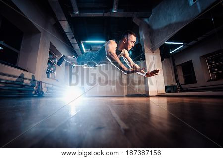 Attractive Muscular Man Doing Push-ups On A Wooden Floor.