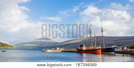 INVERARAY ARGYLL SCOTLAND - SEPTEMBER 26 2014: panorama of the town harbour in the waters of Loch Fyne with two colourful vintage boat and sailboat docked in a bright sunny summer day.
