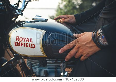India Goa -April 6 2017: Man's hand with a watch on the fuel tank of the Royal Enfield motorcycle.