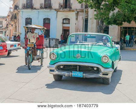 Havana, Cuba - June 30, 2012; Taxi styles on Havana street pedi-cab and green convertible American vintage car moving around city looking for fare.