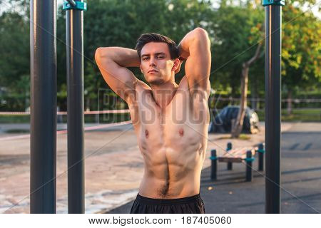 Fitnes man posing on street fitness station showing his muscular body,