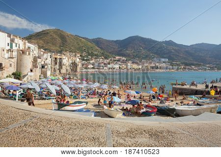 CEFALU,SICILY - JULY. 27. 2016: Unidentified people on sandy beach in Cefalu, Sicily, Italy at Sep 16, 2014. Cefalu is an attractive historic town and seaside resort.