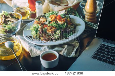 The concept making tasty and healthy food at home. Ingredients and cutlery around fresh salad with shrimps. Serving option