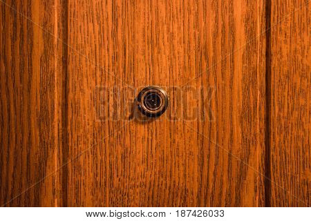 A peephole in the entrance door of a brown color