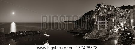 Riomaggiore waterfront view with buildings and moonset in Cinque Terre at night panorama, Italy.