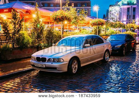 Riga, Latvia - July 3, 2016: Sedan Car BMW 5 Series E39 Parking Near Street Cafe In Evening Or Night Illumination In Old Town On Kalku Street