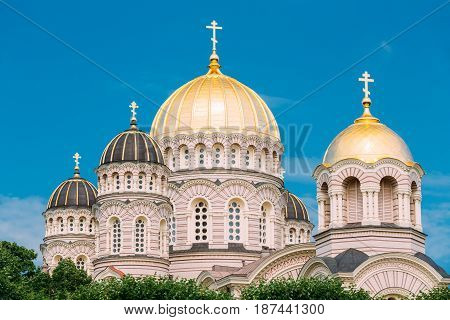 Riga Nativity Of Christ Cathedral - Famous Church And Landmark. Golden Yellow Domes On Blue Sunny Sky Background At Summer Season