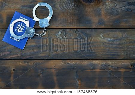 A Ukrainian Passport With Police Handcuffs Lies On A Wooden Table. Problems With The Law During The