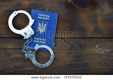 Ukrainian Passport With Police Handcuffs Lies On A Wooden Table. The Concept Of Crime Of Ukrainian C