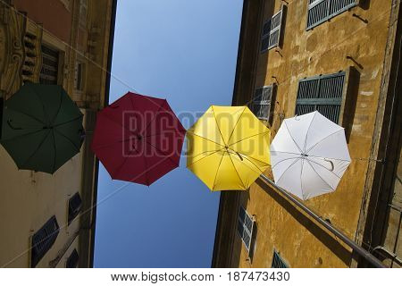 umbrellas of different colors over the street with blue sky as background