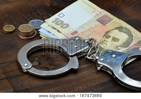 A Photograph Of A Certain Amount Of Ukrainian Money And Police Handcuffs. Concept Of Illegal Earning