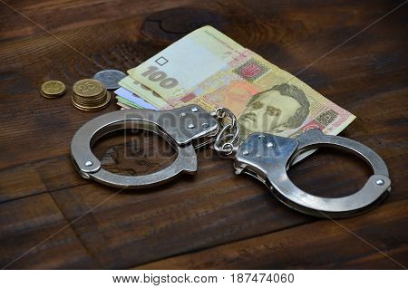 A Photograph Of A Certain Amount Of Ukrainian Money And Police Handcuffs. Concept Of Illegal Earning