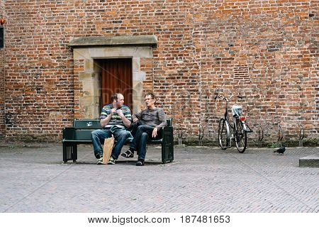 Utrecht Netherlands - August 4 2016: Two men sitting on a publick bench in historic centre of Utrecht the Netherlands