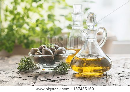 olive oil in glass bottle and olives over old wooden table