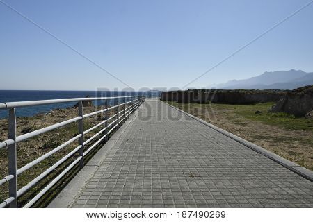 Boardwalk at the seashore outside the village Lapta in the North of Cyprus with clear blue water and blue sky.