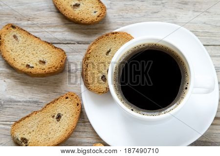 Crunchy toasted bread with raisins and cup of coffee top view, wooden background