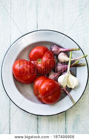 Fresh red tomato on a plate with garlic