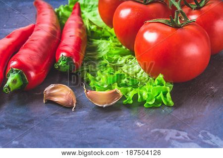Red Chili Peppers, Tomatoes, Sadat And Garlic On A Gray Marble B
