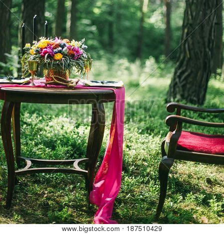 Decorated Wooden Table Served For Two In The Garden On Grass On The Riverbank. Boho And Rustic Style