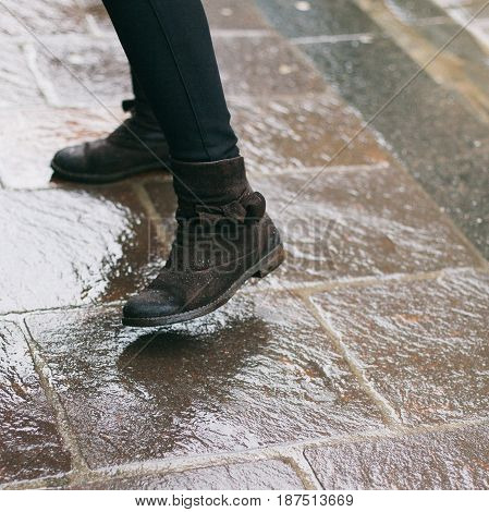 A pedestrian's reflection on the wet concrete pavement on an inclement and wet winter day.