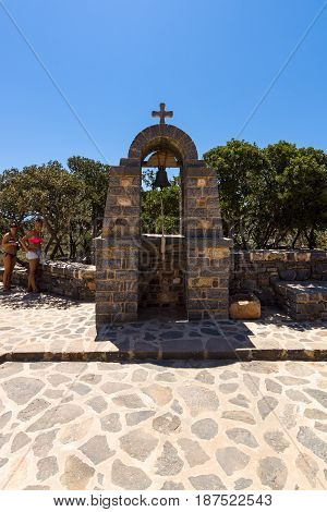 CRETE GREECE - JULY 11 2016: Tourists on Kalydon island near the bell at the top of the hill. Church of St. Luke. Greek Orthodox Church.