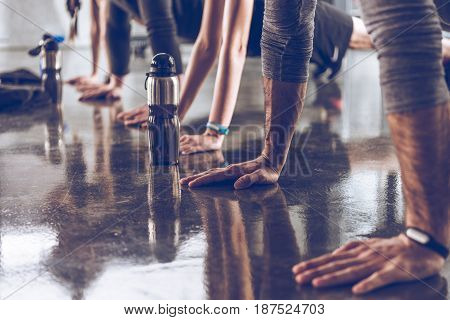 group of athletic young people in sportswear doing push ups or plank at the gym group fitness concept