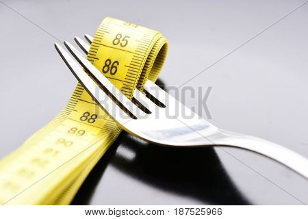 Tape For Measuring Placed Between Tines Of Metal Fork