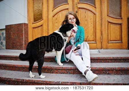 Trendy Girl At Glasses And Ripped Jeans With Russo-european Laika (husky) Dog On A Leash, Against Wo