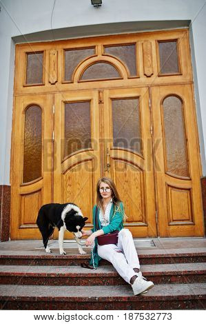 Trendy Girl At Glasses And Ripped Jeans With Russo-european Laika (husky) Dog On A Leash, Against Wo