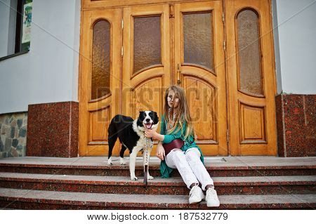 Trendy Girl At Glasses And Ripped Jeans With Russo-european Laika (husky) Dog On A Leash, Against Wo