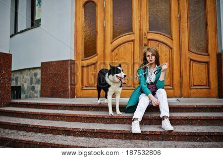 Trendy Girl At Glasses And Ripped Jeans With Russo-european Laika (husky) Dog On A Leash, Against Wo