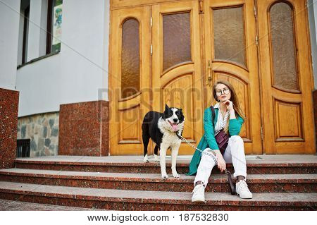 Trendy Girl At Glasses And Ripped Jeans With Russo-european Laika (husky) Dog On A Leash, Against Wo