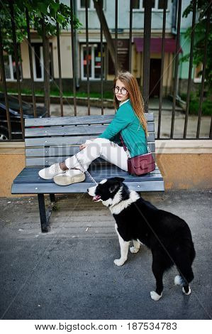 Trendy Girl At Glasses And Ripped Jeans With Russo-european Laika (husky) Dog On A Leash, Against Be