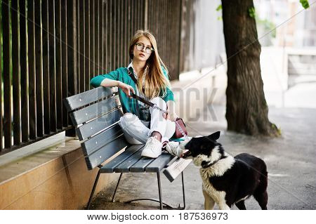 Trendy Girl At Glasses And Ripped Jeans With Russo-european Laika (husky) Dog On A Leash, Against Be