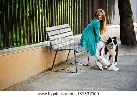 Trendy Girl At Glasses And Ripped Jeans With Russo-european Laika (husky) Dog On A Leash, Against Be