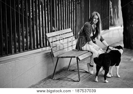 Trendy Girl At Glasses And Ripped Jeans With Russo-european Laika (husky) Dog On A Leash, Against Be