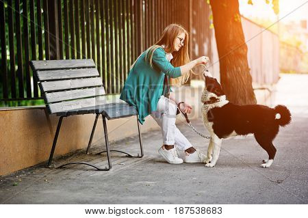 Trendy Girl At Glasses And Ripped Jeans With Russo-european Laika (husky) Dog On A Leash, Against Be