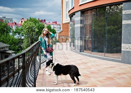 Trendy Girl At Glasses And Ripped Jeans With Russo-european Laika (husky) Dog On A Leash, Against Bu