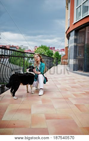 Trendy Girl At Glasses And Ripped Jeans With Russo-european Laika (husky) Dog On A Leash, Against Bu