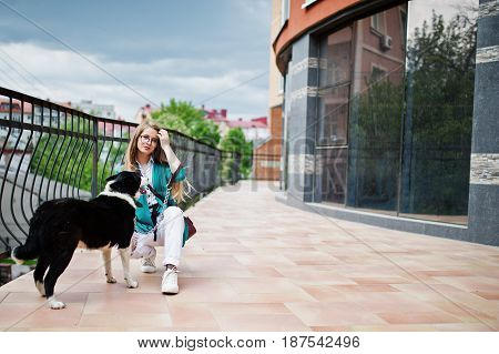 Trendy Girl At Glasses And Ripped Jeans With Russo-european Laika (husky) Dog On A Leash, Against Bu