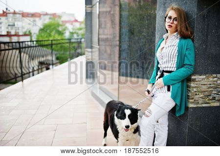 Trendy Girl At Glasses And Ripped Jeans With Russo-european Laika (husky) Dog On A Leash, Against St