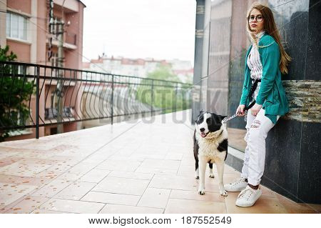 Trendy Girl At Glasses And Ripped Jeans With Russo-european Laika (husky) Dog On A Leash, Against St