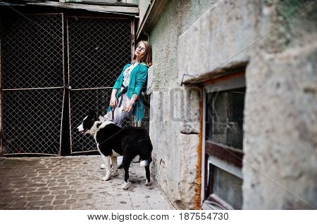 Trendy Girl At Glasses And Ripped Jeans With Russo-european Laika (husky) Dog On A Leash, Against St