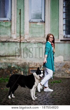 Trendy Girl At Glasses And Ripped Jeans With Russo-european Laika (husky) Dog On A Leash, Against St