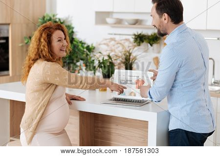 Family moments. Extremely happy married couple choosing clothes on an internet site, both wearing casual attire and grinning broadly.