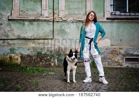 Trendy Girl At Glasses And Ripped Jeans With Russo-european Laika (husky) Dog On A Leash, Against St