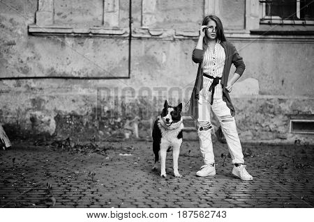 Trendy Girl At Glasses And Ripped Jeans With Russo-european Laika (husky) Dog On A Leash, Against St