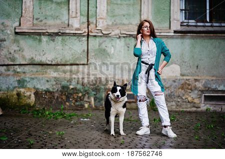 Trendy Girl At Glasses And Ripped Jeans With Russo-european Laika (husky) Dog On A Leash, Against St